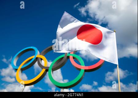 RIO DE JANEIRO - MARS 2016 : un drapeau japonais flotte dans le vent devant les anneaux olympiques debout sous un ciel bleu vif avec des nuages blancs bouffis Banque D'Images