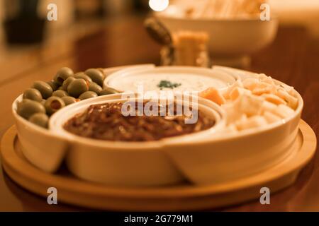 Trempettes de fromage, oignons, olives et salsa servies dans des bols sur une table. Arrière-plan flou. Banque D'Images