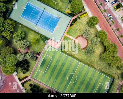 Un tir de drone de terrain de mini-football vide et un terrain de ténis entouré d'un parc et d'arbres dans une communauté fermée à l'extérieur de Guayaquil City, en Équateur. Banque D'Images