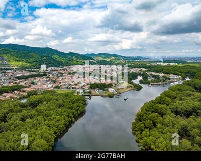 Vue aérienne par drone des mangroves à densité élevée dans le golfe de Guayaquil, en Equateur, volant et regardant vers quelques communautés et maisons fermées. Banque D'Images