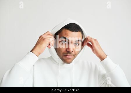 Portrait minimal d'un jeune homme latino-américain portant un sweat à capuche blanc et regardant l'appareil photo, l'espace de copie Banque D'Images