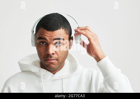 Portrait minimal d'un homme latino-américain moderne portant un casque à capuche blanc tout en regardant l'appareil photo, l'espace de copie Banque D'Images