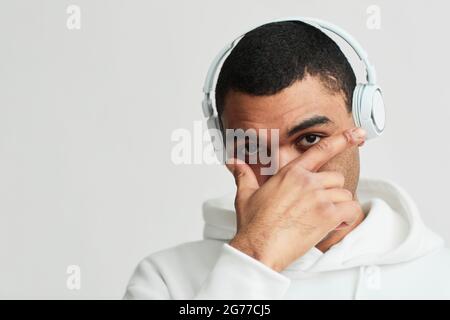 Portrait minimal d'un homme latino-américain portant un casque et un sweat à capuche blanc tout en regardant l'appareil photo, l'espace de copie Banque D'Images