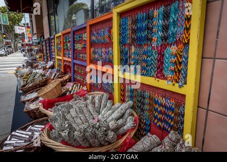 Bijoux en perles indigènes de style Huichol à vendre avec des paquets de sauge et d'autres articles le long du trottoir dans le quartier de Mission, San Francisco. Banque D'Images