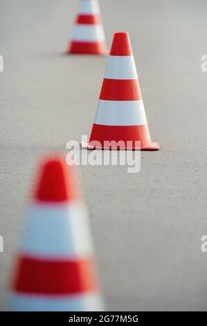 Cônes de signalisation orange vif prêts pour le slalom sur une surface en asphalte. Banque D'Images