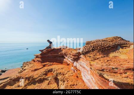 Tourisme assis sur les falaises rouges de Pindan le long de la côte à la renommée Gantheaume point, Broome, Australie occidentale, WA, Australie Banque D'Images