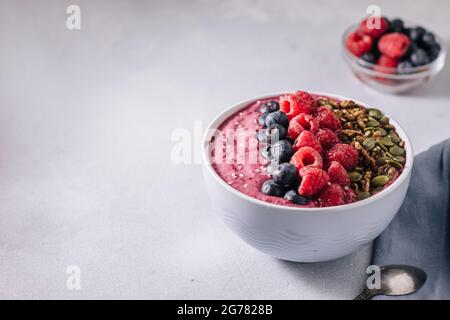 Bol de smoothies Acai aux framboises, aux bleuets, aux noix, aux graines de citrouille et au sésame Banque D'Images