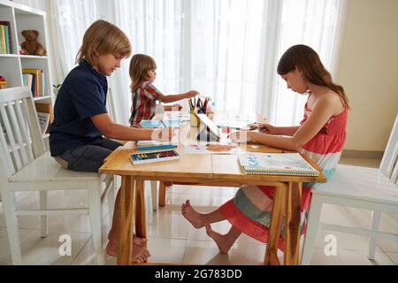 Groupe d'enfants passant du temps ensemble dans la salle de jeux, de dessiner des images et de réaliser Banque D'Images