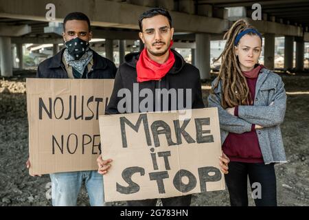 Une jeune rébellion multi-ethnique confiante, des personnes debout avec des signes et se protégeant contre l'injustice du gouvernement Banque D'Images