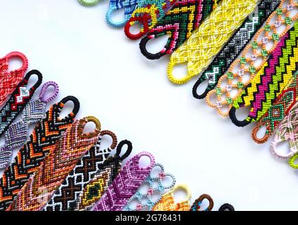 Tissées bracelets d'amitié à la main de broderie fil brillant avec noeuds sur fond blanc. Banque D'Images