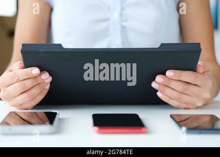 Une femme tient une tablette sur une table trois smartphones se trouvent Banque D'Images