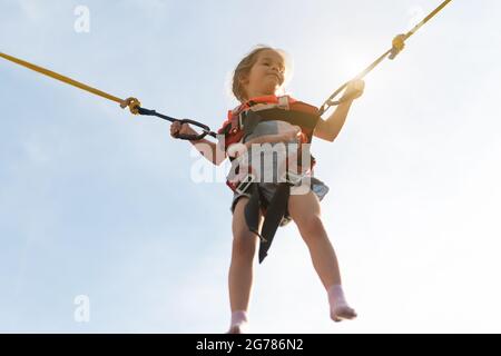 Enfant saut enfant trampoline élastiques bandes parc d'attractions petite fille saut sur l'attraction Banque D'Images