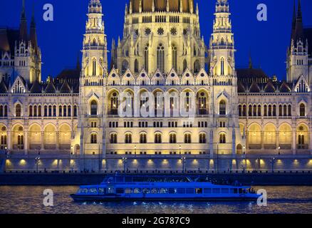 Budapest, Hongrie. 26 juin 2021. Un bateau d'excursion navigue le long du Danube dans la soirée, devant le siège éclairé du Parlement hongrois. Credit: Robert Michael/dpa-Zentralbild/ZB/dpa/Alay Live News Banque D'Images