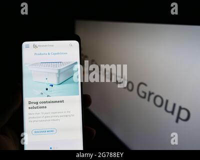 Personne tenant un smartphone avec le site Web de la société italienne de verre Stevanato Group spa sur écran avec logo. Concentrez-vous sur le centre de l'écran du téléphone. Banque D'Images