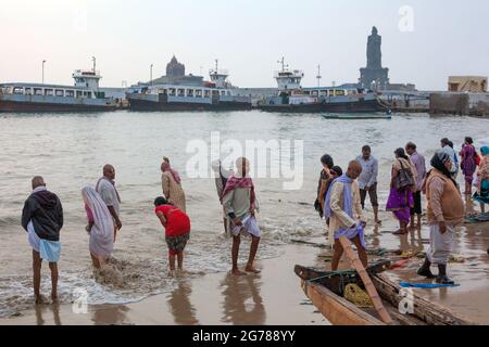 Les adorateurs hindous se baignent tôt le matin dans l'océan au monument commémoratif de Vivekananda Rock et à la statue de Thiruvalluvar, Kanyakumari, Tamil Nadu, Inde Banque D'Images