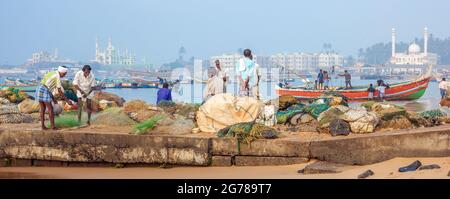 Panorama des pêcheurs indiens qui se tenaient sur le front de mer à Vizhinjam avec des mosquées en arrière-plan, Kerala, Inde Banque D'Images