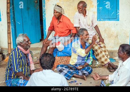 Groupe de pêcheurs hors service assis sur des cartes à jouer au sol, Vizhinjam, Kerala, Inde Banque D'Images