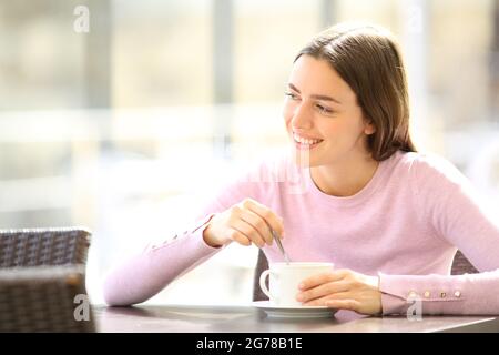 Bonne femme qui agite un café assis sur la terrasse du restaurant Banque D'Images