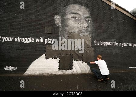 Ed Wellard, de Withington, fait passer des bandes-poubelles sur des textes offensifs sur la fresque de l'attaquant de Manchester United et du joueur d'Angleterre Marcus Rashford sur le mur du Coffee House Cafe sur Copson Street, Withington, qui semblait vandalisé le matin après que l'équipe de football d'Angleterre ait perdu la finale de l'UEFA Euro 2021. Date de la photo: Lundi 12 juillet 2021. Banque D'Images