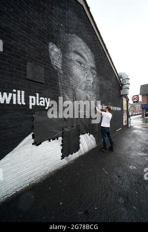 Ed Wellard, de Withington, fait passer des bandes-poubelles sur des textes offensifs sur la fresque de l'attaquant de Manchester United et du joueur d'Angleterre Marcus Rashford sur le mur du Coffee House Cafe sur Copson Street, Withington, qui semblait vandalisé le matin après que l'équipe de football d'Angleterre ait perdu la finale de l'UEFA Euro 2021. Date de la photo: Lundi 12 juillet 2021. Banque D'Images