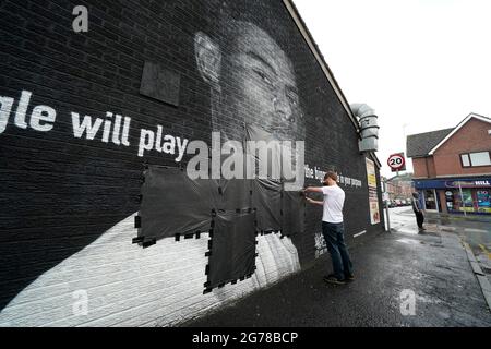 Ed Wellard, de Withington, fait passer des bandes-poubelles sur des textes offensifs sur la fresque de l'attaquant de Manchester United et du joueur d'Angleterre Marcus Rashford sur le mur du Coffee House Cafe sur Copson Street, Withington, qui semblait vandalisé le matin après que l'équipe de football d'Angleterre ait perdu la finale de l'UEFA Euro 2021. Date de la photo: Lundi 12 juillet 2021. Banque D'Images