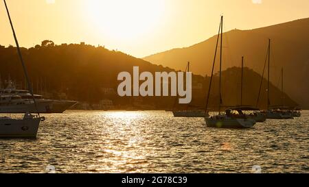 Iles Ioniennes, Ithaka, Baie de Molos, Vathi, crépuscule, Coucher de soleil, vue de Vathi sur la baie avec des bateaux à voile, soleil sur les collines, ciel de sable, mer légèrement en mouvement, sunbeam sur l'eau Banque D'Images