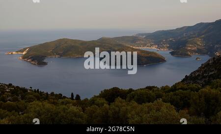 Iles Ioniennes, Ithaka, île d'Odysseus, capitale, Vathi, Vue de dessus de la baie de Molos, collines vertes en premier plan, la baie de Vathi en haut à droite dans la photo, collines vertes tout autour, mer bleue, ciel bleu clair à blanc Banque D'Images