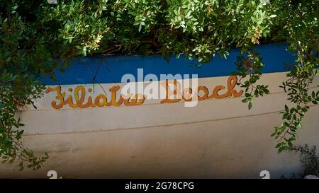 Iles Ioniennes, Ithaka, île d'Odysseus, près de Vathi, Plage de Filiatro, Plage de galets, bateau tiré à terre sous les buissons avec l'inscription « Plage de Filiatro » Banque D'Images