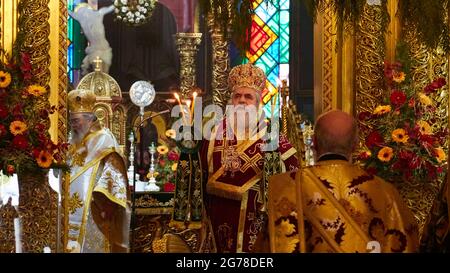 Îles Ioniennes, Zakynthos, ville de Zakynthos, Église de Saint Dionysius, Fête de Saint Dionysius le 17 décembre, trois membres du clergé orthodoxe sont debout devant le chœur, de splendides robes, des bougies sont allumées, vitraux en arrière-plan Banque D'Images