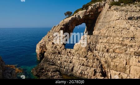 Îles Ioniennes, Zakynthos, côte ouest, Mer Adriatique, Korakonissi, rock island, porte de pierre, trou dans l'île, à travers le trou vous pouvez voir un bateau à voile blanc sur la mer ouverte Banque D'Images