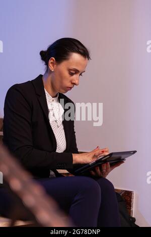 Femme d'affaires stressée sous pression pour terminer l'échéance de travail faisant des heures supplémentaires la nuit. Entrepreneur sérieux travaillant sur le projet d'emploi assis sur l'escalier de bâtiment d'affaires à la nuit heures pour le travail. Banque D'Images