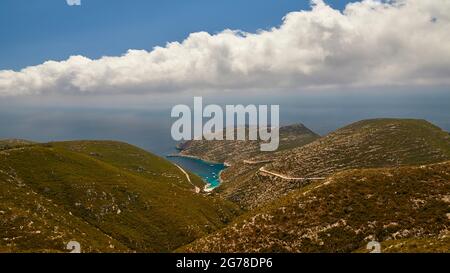 Iles Ioniennes, Zakynthos, côte ouest, Mer Adriatique, plage, Port, Porto Vromi, vue de très loin au-dessus de la petite baie profondément indentée, eau vert-bleu dans la baie, collines surcultivées à gauche et à droite au-dessus de la baie, La route sur la droite mène vers le ciel bleu du port avec un long mur de nuages blancs sur toute la largeur de l'image Banque D'Images