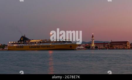 Zakynthos, ville de Zakynthos, prise de vue de nuit, prise de vue de soir, coucher de soleil dans le ciel, tendre, port, ferry de Zante illuminé au milieu de la distance, eau en premier plan, église illuminée d'Agios Dionysios juste derrière le ferry, tour d'église fésiée Banque D'Images