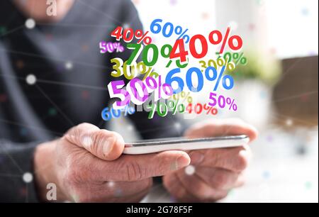 Mains de l'homme tenant un smartphone avec le concept de pourcentage de remise Banque D'Images