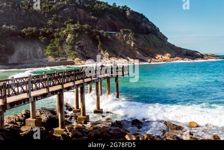 Pier at Beach - jetée avec pêcheurs à Victoria Bay dans l'ouest du Cap Afrique du Sud - plage de surf populaire pour les surfeurs dans tout le pays. Banque D'Images