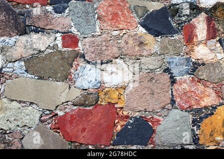 Texture du mur avec des blocs de pierre de couleurs rouge, jaune, vert et gris. Arrière-plan horizontal avec mosaïque décorative en pierre Banque D'Images