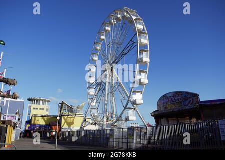 Ferris Wheel au parc d'attractions de bord de mer contre un ciel bleu clair Banque D'Images