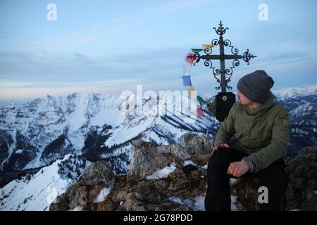 Vue de l'Auerspitze (1811m) vers Krenspitze (1972m), Hinteres Sonnwendjoch, homme assis devant la croix du sommet, Europe, Allemagne, Bavière, haute-Bavière,Alpes bavaroises, montagnes de Mangfall, Spitzingsee Banque D'Images