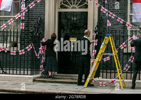 LONDRES 12 juillet 2021. Les membres du personnel délèvent le bunkting d'Angleterre autour de la porte du 10 Downing Street un jour l'équipe nationale de football d'Angleterre avait perdu la finale de l'UEFA Euro 2020 pour des sanctions contre l'Italie à Wembley le dimanche 11 juillet. Les joueurs d'Angleterre Marcus Rashford, Jadon Sancho et Bukayo Saka ont été ciblés sur les médias sociaux avec des abus raciaux après avoir manqué leurs sanctions lors de la fusillade qui a porté la victoire à l'équipe italienne. Credit amer ghazzal/Alamy Live News Banque D'Images