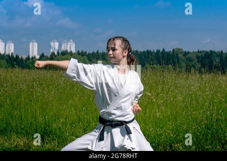 une jeune fille qui exécute kata de karaté à l'extérieur dans la position kiba-dachi Banque D'Images