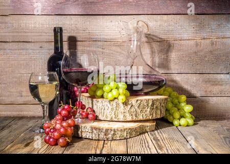 Verres de vin rouge et blanc avec soleil et ombres, avec bouteille et décanter, bouquet de raisins, sur fond de bois avec tourteaux biologiques, autum Banque D'Images