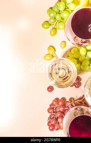 Verres de vin rouge et blanc avec soleil et ombres, avec bouteille et carafe, bouquet de raisins, sur fond crémeux, vue sur le dessus plat vin Banque D'Images