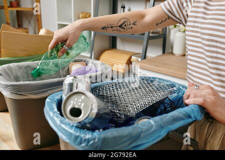 Femme avec tatouage sur bras triant les déchets et le mettant dans différents bacs Banque D'Images