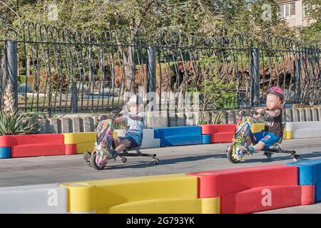 Sudak, Ukraine - 12 juin 2021 : deux petits garçons qui sont à bord d'un scooter électrique de kart dans un parc d'attractions par une journée ensoleillée d'été. Banque D'Images