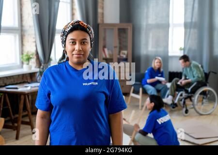Volontaire de course mixte en t-shirt bleu foncé debout contre ses collègues Banque D'Images