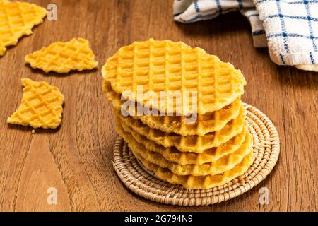 Une pile de gaufres croustillantes maison sur un tapis en bambou avec des morceaux de gaufres croustillantes cassées et un linge de table sur une table en bois. Banque D'Images