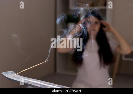 Un bâton indien aromatique est en train de brûler, la femme en arrière-plan est méditant. L'aromathérapie, l'auto-immersion, le pouvoir de la pensée Banque D'Images