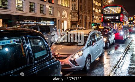 Circulation à Londres. Une circulation nocturne s'est embârée dans les rues humides de Londres's Strand avec des bus rouges familiers et des taxis noirs parmi la circulation. Banque D'Images