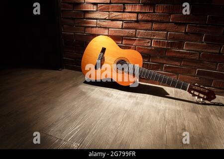 Guitare classique sur mur de briques ; guitare acoustique sur éclairage sombre Banque D'Images