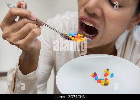 Dans le foyer sélectif de Crazy femmes mangeant beaucoup de pilules dans cuiller.moment dramatique. Banque D'Images